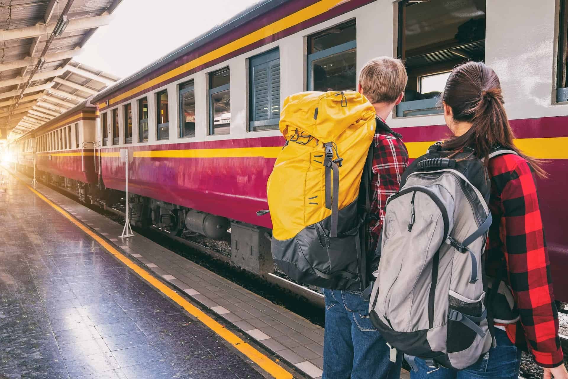 Man en vrouw met een backpack om staan voor een trein op het station.
