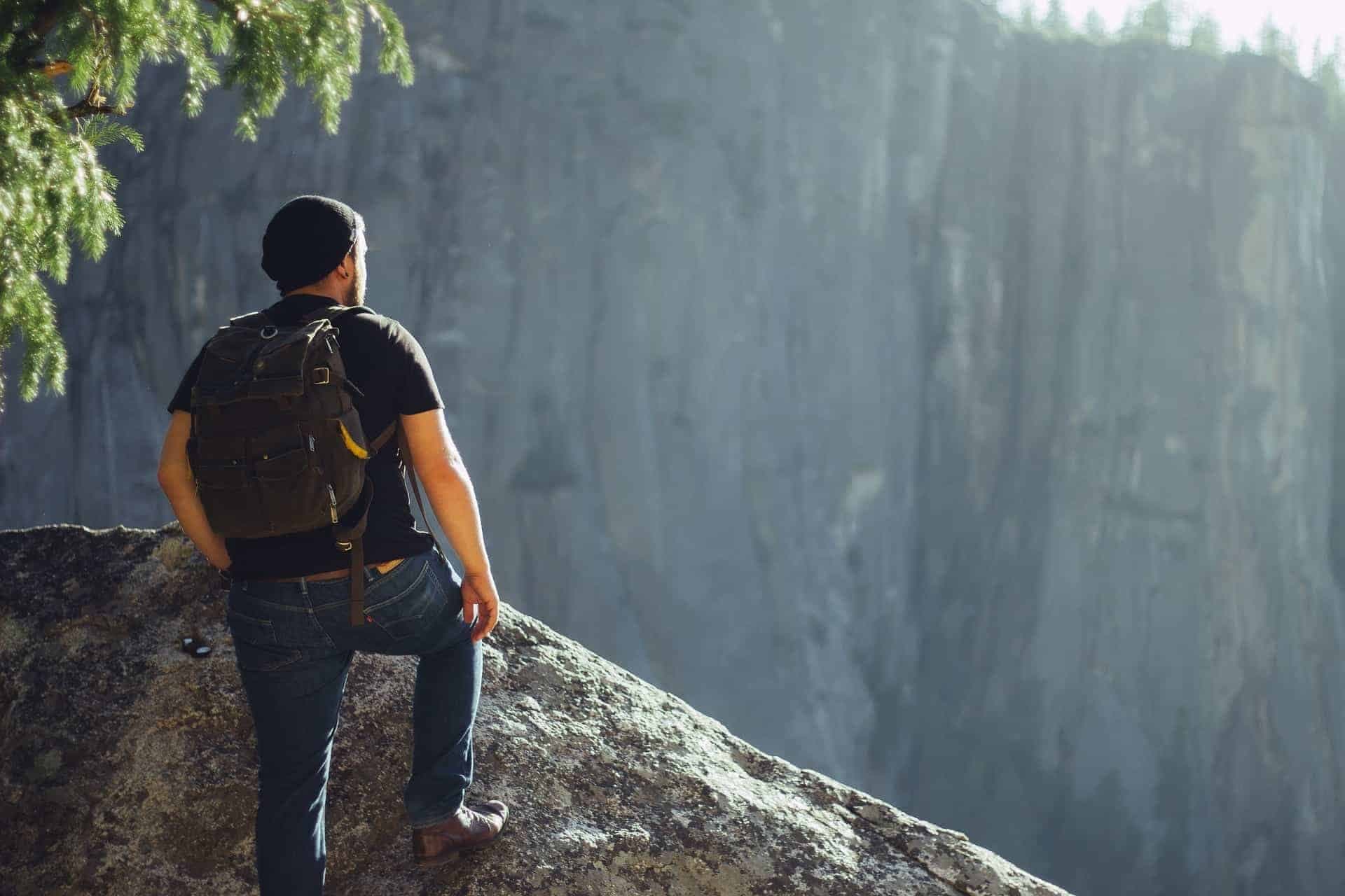Man met backpack staat op een steen.