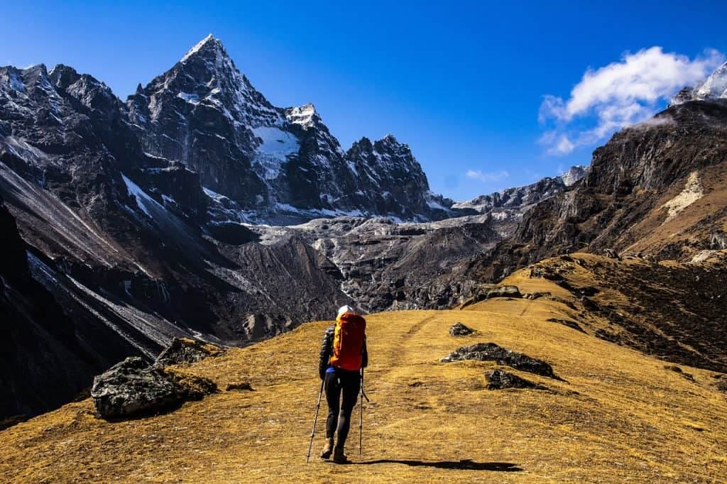 Mount Everest met besneeuwde toppen en wandelaars op een trektocht tegen een helderblauwe lucht.