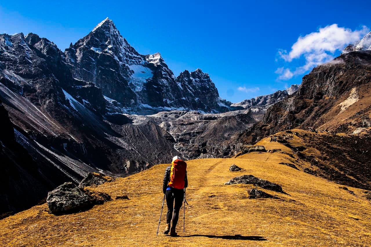 Mount Everest met besneeuwde toppen en wandelaars op een trektocht tegen een helderblauwe lucht.